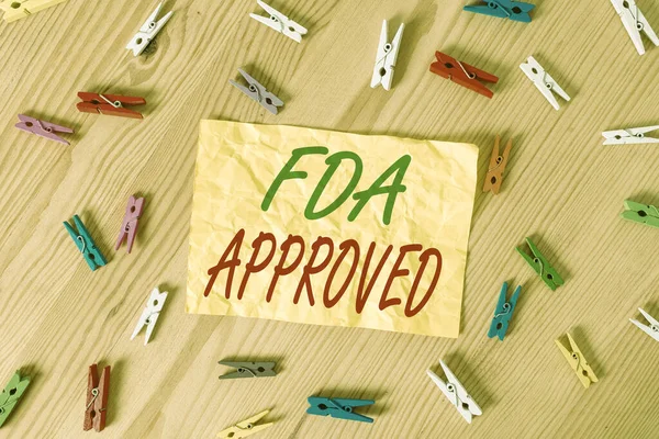 Az FDA jóváhagyását igazoló levél. Üzleti fotó bemutató FDA megállapodott a termék vagy képlet biztonságos és hatékony Színes ruhacsap papírok üres emlékeztető fa padló háttér iroda. — Stock Fotó