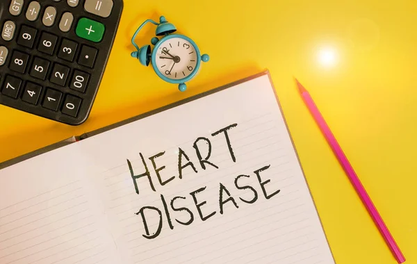 Writing note showing Heart Disease. Business photo showcasing class of diseases that involve the heart or blood vessels Open striped notebook calculator metal alarm clock color background. — Stock Photo, Image
