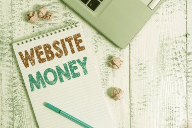 Web sitesinin parasını gösteren kavramsal el yazısı. İş fotoğrafı tanıtımı, paranın kazanıldığı, dizüstü bilgisayarın spiral not defteri ezdiği kağıt toplar, ahşap masa anlamına gelir..
