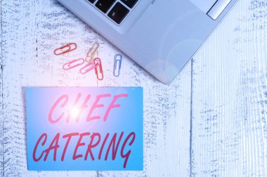 Şef Yemekçiyi gösteren bir not yazıyorum. İş fotoğraflarının sergilenmesi çeşitli etkinlikler için servis, yiyecek ve içecekler sağlar. Moda metalik dizüstü bilgisayar boş yapışkan notalar eski masadaki renkli klipler.