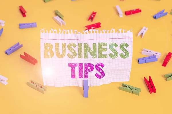 Word writing text Business Tips. Business concept for tricks or ideas on how to start or run a small business Colored clothespin papers empty reminder yellow floor background office.