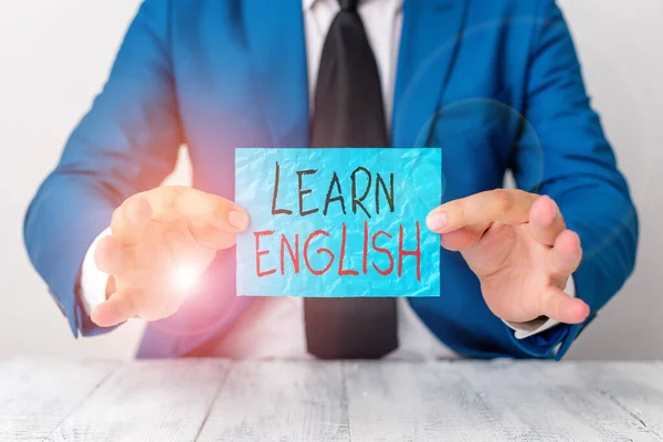 Text sign showing Learn English. Conceptual photo gain or acquire knowledge of speaking and writing English Man holds empty paper with copy space in front of him Copy Space.