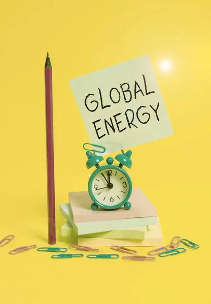 Skriver lapp som visar Global Energy. Business photo showcasing Världsomspännande makt från källor såsom el och kol väckarklocka klibbig not staplade anteckningsblock penna färgad bakgrund. — Stockfoto