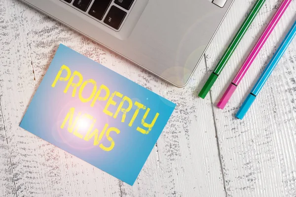 Tekstbord met eigendomsnieuws. Conceptuele foto Het kopen of verkopen, en het huren van land of het bouwen van Trendy metalen laptop blanco plakkerige pad drie pennen liggen vintage tafel. — Stockfoto