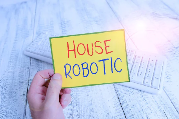 Handwriting text House Robotic. Concept meaning Programmable powered machines that perform household chores man holding colorful reminder square shaped paper white keyboard wood floor.
