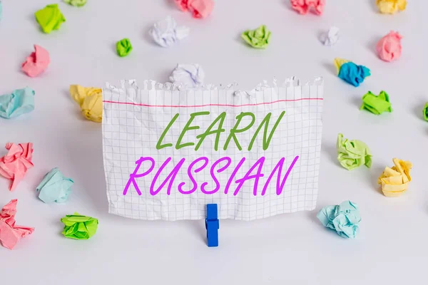 Handwriting text writing Learn Russian. Concept meaning gain or acquire knowledge of speaking and writing Russian Colored crumpled papers empty reminder white floor background clothespin.