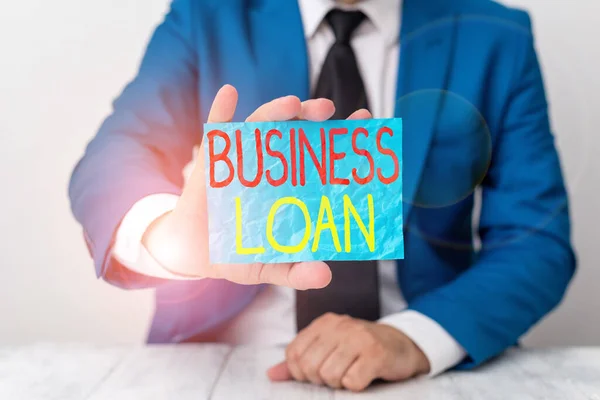 Writing note showing Business Loan. Business photo showcasing Loans provided to small businesses for various purposes Man holds empty paper with copy space in front of him Space.