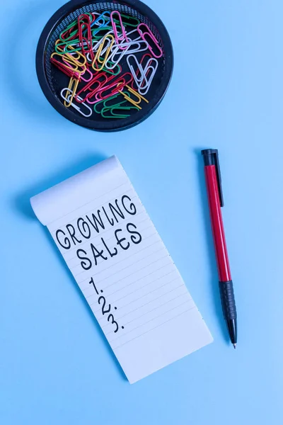 Conceptual hand writing showing Growing Sales. Business photo text Average sales volume of a company products has grown Notebook and stationary with mouse above pastel backdrop. — Stock Photo, Image