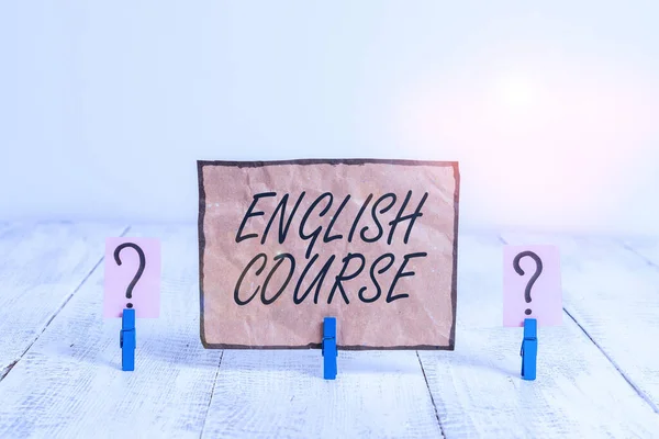 Writing note showing English Course. Business photo showcasing courses cover all levels of speaking and writing in english Crumbling sheet with paper clips placed on the wooden table.