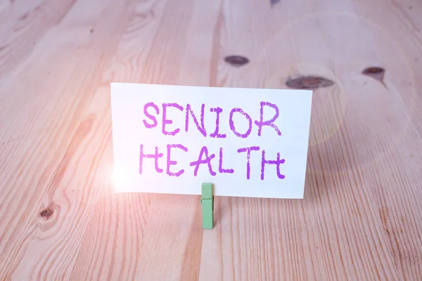Conceptual hand writing showing Senior Health. Business photo showcasing refers to physical and mental conditions of senior citizens Wooden floor background green clothespin groove slot office.