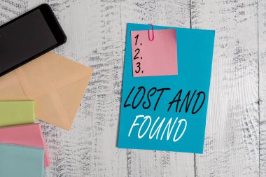 Kayıp Eşyalar 'ı gösteren kavramsal el yazısı. Zarar görmüş eşyaların saklandığı bir yeri gösteren bir iş fotoğrafı. Zarf kağıdı, akıllı telefon, ahşap arka plan..