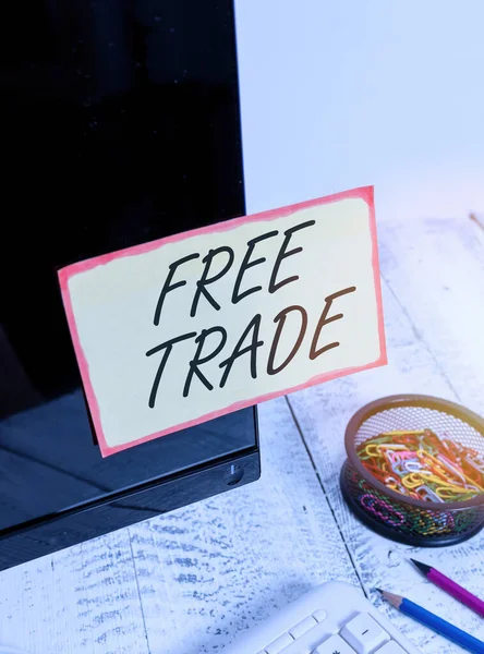 Writing note showing Free Trade. Business photo showcasing international trade left to its natural course without tariffs Note paper taped to black computer screen near keyboard and stationary.