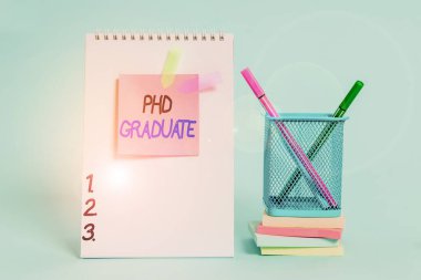 Doktora derecesini gösteren bir mesaj. Kurstan sonra verilen kavramsal fotoğraf en yüksek üniversite diploması. Spiral not defteri yapışkan not pankartları istiflenmiş kalem tutucu pastel geri.