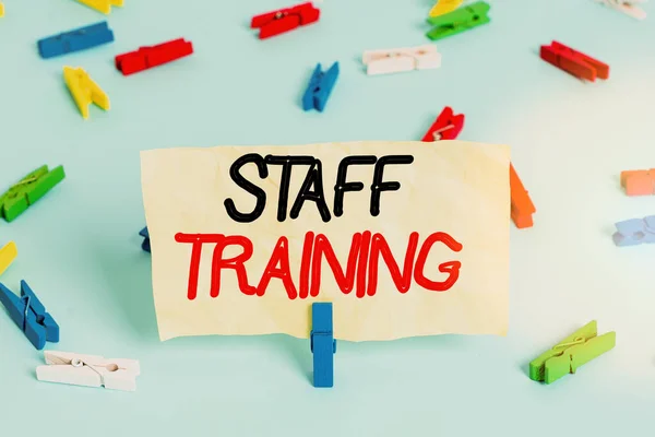 Text sign showing Staff Training. Conceptual photo learn specific knowledge improve performance in current roles Colored clothespin papers empty reminder blue floor background office pin.