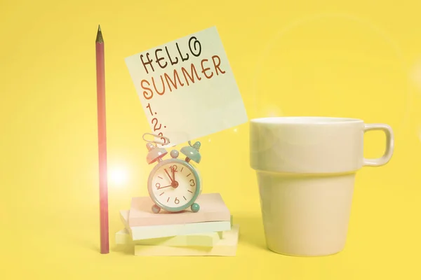 Письменный текст Hello Summer. Бизнес-концепция на сезон после весны и до осени, где погода горячая Будильник кофе чашки ноты сложены блокноты карандаш цветной фон . — стоковое фото