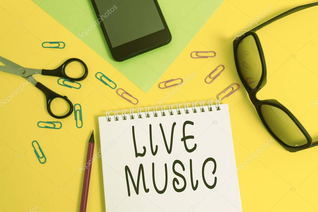 Writing note showing Live Music. Business photo showcasing performance given by one or more singers or instrumentalists Sheet pencil smartphone scissors eyeglasses notepad color background.