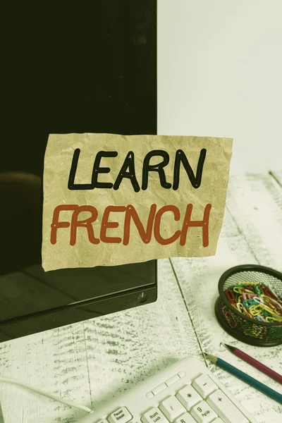 Text sign showing Learn French. Conceptual photo get knowledge or skill in speaking and writing French language Note paper taped to black computer screen near keyboard and stationary.