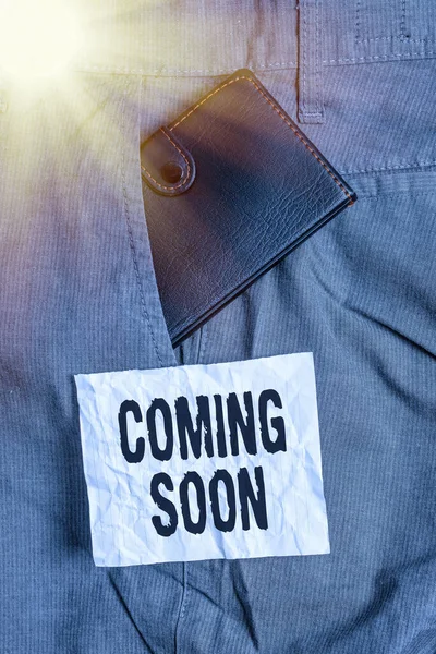 Text sign showing Coming Soon. Conceptual photo event or action that will happen after really short time Small little wallet inside man trousers front pocket near notation paper.