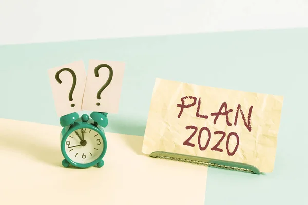 Konzeptionelle Handschrift mit Plan 2020. Geschäftsfoto mit detailliertem Vorschlag, im nächsten Jahr etwas zu tun oder zu erreichen. Wecker neben einem Papierblatt auf pastellfarbenem Hintergrund.. — Stockfoto