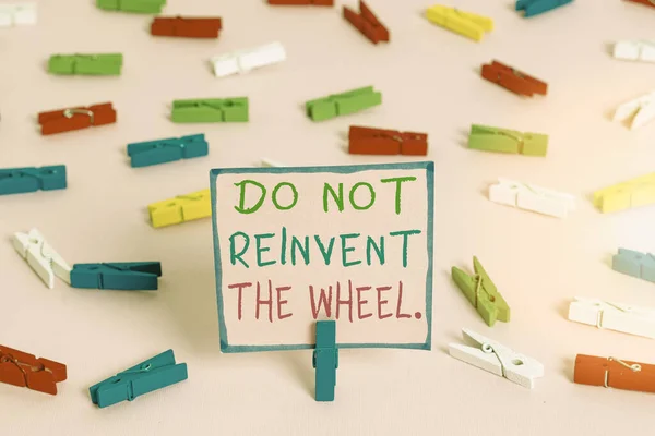 Word writing text Do Not Reinvent The Wheel. Business concept for stop duplicating a basic method previously done Colored clothespin papers empty reminder pink floor background office pin.