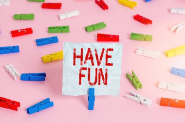 İyi Eğlenceler 'i gösteren not yazıyorum. İş fotoğrafı tanıtımı. Renkli çamaşır iğnesi kağıtları. Pembe ofis rozeti..