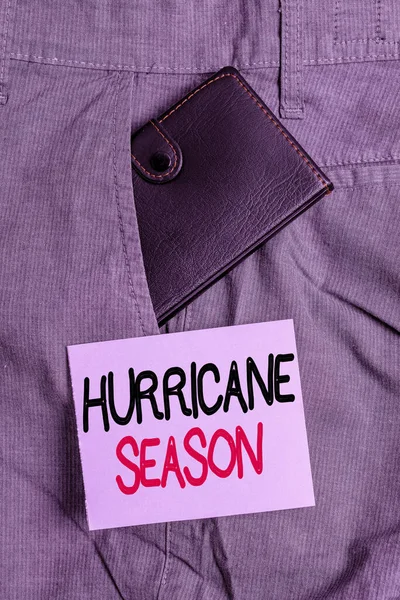 ハリケーンシーズンを示すメモを書く。ほとんどの熱帯低気圧が発達することが予想される時間を紹介するビジネス写真表記紙の近くのズボンのフロントポケット内の小さな財布. — ストック写真
