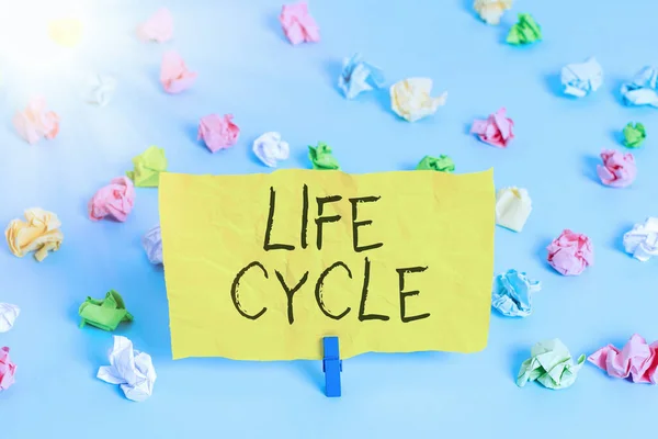 Handwriting text writing Life Cycle. Concept meaning the series of changes in the life of an organism and animals Colored crumpled papers empty reminder blue floor background clothespin.