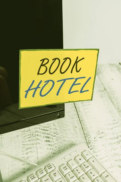 A Book Hotel felirata. Business photo showcasing an arrangement you make to have a hotel room or accommodation Notation paper computer monitor screen near white keyboard. — Stock Fotó