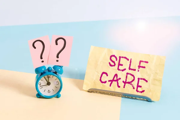 Conceptual hand writing showing Self Care. Business photo showcasing practice of taking action to preserve or improve ones own health Alarm clock beside a Paper sheet placed on pastel backdrop. — Stock Photo, Image