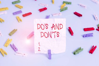 Dos And Don 't T.S.' i gösteren bir not yazıyorum. Bazı faaliyet veya eylemlerle ilgili kural ve gelenekleri gösteren iş fotoğrafı. Renkli çamaşır iğnesi kağıtları boş hatırlatıcı mavi zemin ofis.