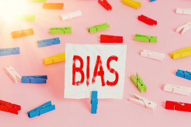 Bias 'ı gösteren bir not yazıyorum. Renkli çamaşır iğnesi kağıtlarının boş hatırlatıcı pembe ofis rozeti olduğunu gösteren bir grup için eğilim ya da önyargı gösteren iş fotoğrafı.