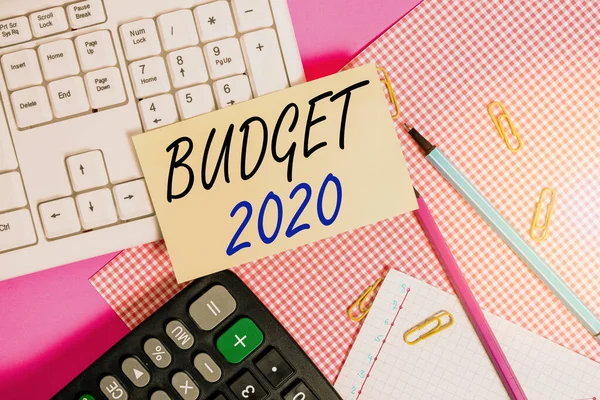 Handwriting text Budget 2020. Concept meaning estimate of income and expenditure for next or current year Note paper stick to computer keyboard near colored gift wrap sheet on table.
