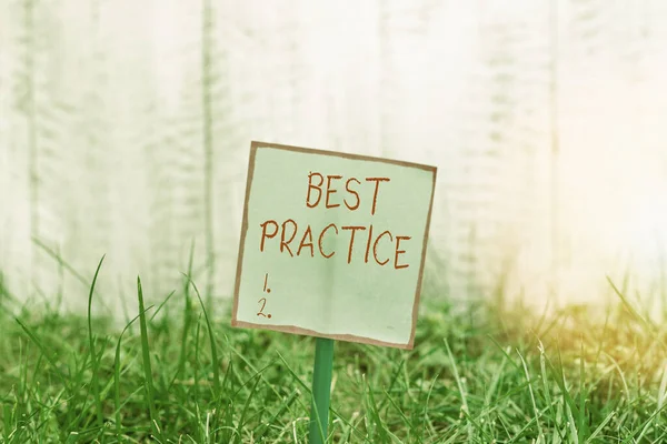 Word writing text Best Practice. Business concept for commercial procedures that are accepted prescribed being correct Plain empty paper attached to a stick and placed in the green grassy land.