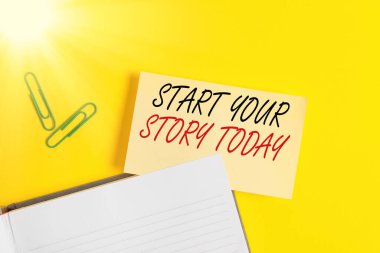 Hikayeni Bugün Başlat 'ı gösteren bir not yazıyorum. İş fotoğrafı sergisi sıkı çalışın ve şu andan itibaren sarı masada fotokopi alanı olan boş turuncu kağıt ile başlayın..