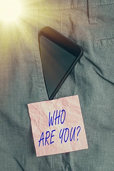 Textschild mit der Frage "Wer bist du?" Konzeptfoto, bei dem eine demonstrierende Identität oder persönliche Informationen verlangt werden Smartphone-Gerät in der Arbeitshosentasche in der Nähe von Notizpapier. — Stockfoto