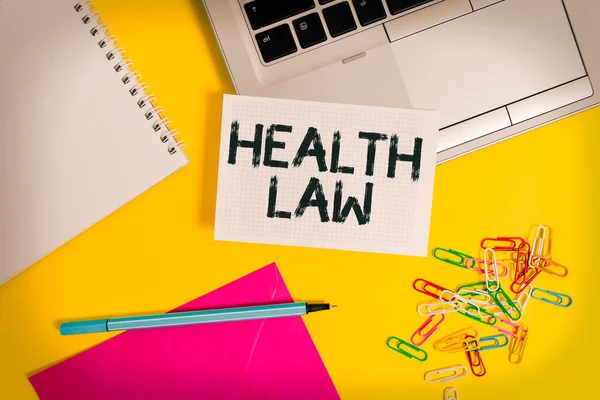 Writing note showing Health Law. Business photo showcasing law to provide legal guidelines for the provision of healthcare Laptop marker squared sheet spiral notebook envelope colored background.