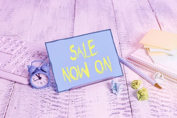 Handwriting text writing Sale Now On. Concept meaning Discounts and promotional sales retail marketing offer Notepaper stand on buffer wire in between computer keyboard and math sheets.