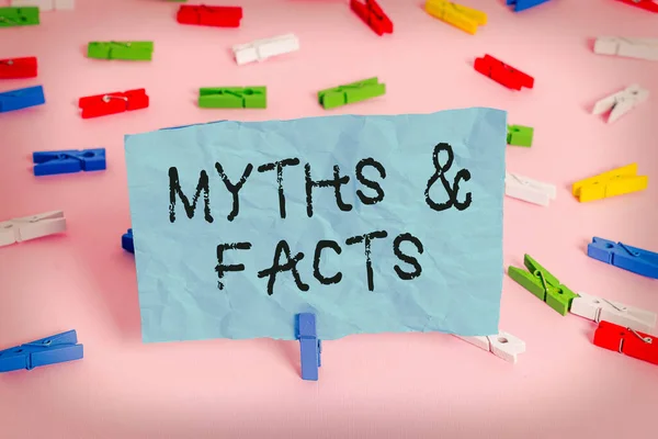 Conceptual hand writing showing Myths And Facts. Business photo showcasing usually traditional story of ostensibly historical events Colored clothespin papers empty reminder pink floor office. — Stock Photo, Image