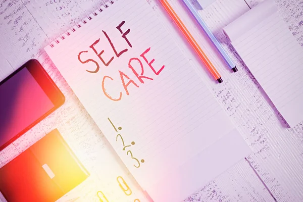 Handwriting text Self Care. Concept meaning the practice of taking action to improve one own health Smartphone man wallet clips notebook pens ballpoints note pad wooden table. — Stock Photo, Image
