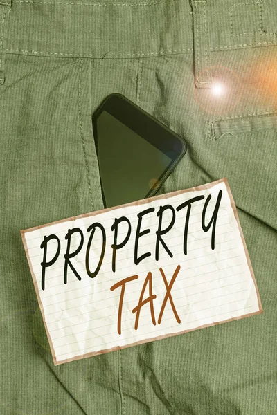 Text sign showing Property Tax. Conceptual photo an ad valorem tax on the value of a property Millage rate Smartphone device inside formal work trousers front pocket near note paper.