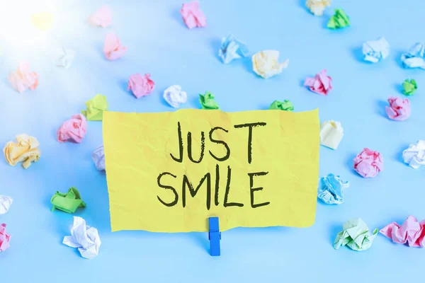Scrivere testi a mano Just Smile. Concetto significato assumere un'espressione facciale che indica piacere o divertimento Colori carta spiegazzata vuoto promemoria blu pavimento sfondo molletta . — Foto Stock