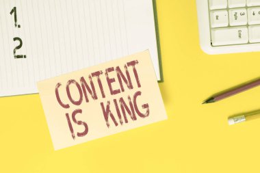 İçeriğin Kral olduğunu gösteren mesaj işareti. Kavramsal fotoğraf pazarlaması, ödenmemiş arama sonuçlarına odaklandı. Sarı masada fotokopi alanı olan boş turuncu kağıt..