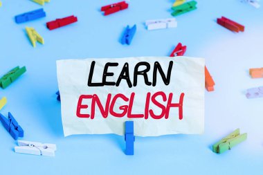 İngilizce öğrenmeyi gösteren metin işareti. Kavramsal fotoğraf kazancı, Renkli çamaşır iğnesi kağıtları boş hatırlatıcı mavi zemin ofis broşu çalışarak yeni dilde bilgi edinir.