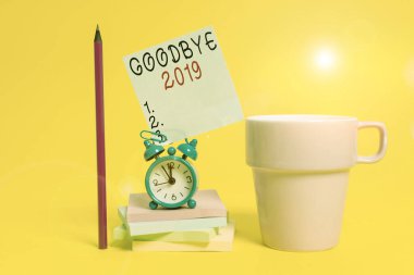 Kelime yazma metni Elveda 2019. Yıl sonunda ayrılık sırasında iyi dileklerini dile getirme konsepti. Alarm saati kahve fincanı notu dizilmiş kalem renkli arka plan.