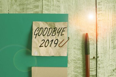 Elveda 2019 yazılı mesaj. Yılın sonunda ayrılırken iyi dileklerini ifade eden kavramsal fotoğraf. Kırışıklık kağıdı ve karton artı ahşap arka planın üzerine yerleştirilmiş sabit..