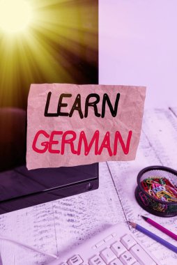 Almanca Öğren 'i gösteren metin işareti. Kavramsal fotoğraf Almanca konuşma ve yazmada bilgi veya beceri kazan. Klavye ve durağanlık yakınındaki siyah bilgisayar ekranına yapıştırılmış not kağıdı..