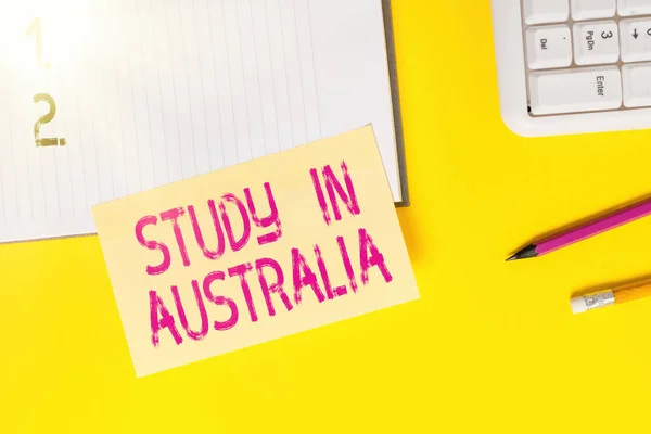 Avustralya 'da Çalışma Yazısı. Yabancı ülke düzenine giren kavramsal fotoğraf eğitiminizi tamamlayın. Sarı masada fotokopi alanı olan boş turuncu kağıt. — Stok fotoğraf
