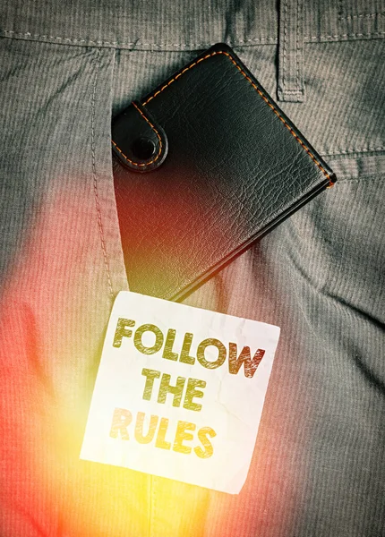 Word writing text Follow The Rules. Business concept for go with regulations governing conduct or procedure Small little wallet inside man trousers front pocket near notation paper. — Stock Photo, Image