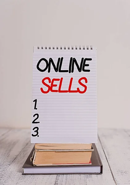 Conceptual hand writing showing Online Sells. Business photo text sellers directly sell goods or services over the Internet Front view stacked books spiral note book on vintage wooden table.