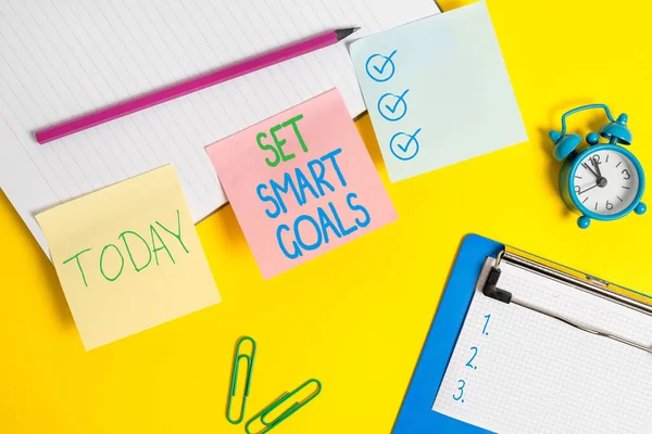 Text sign showing Set Smart Goals. Conceptual photo list to clarify your ideas focus efforts use time wisely Flat lay above table with blank papers with copy space for text messages.